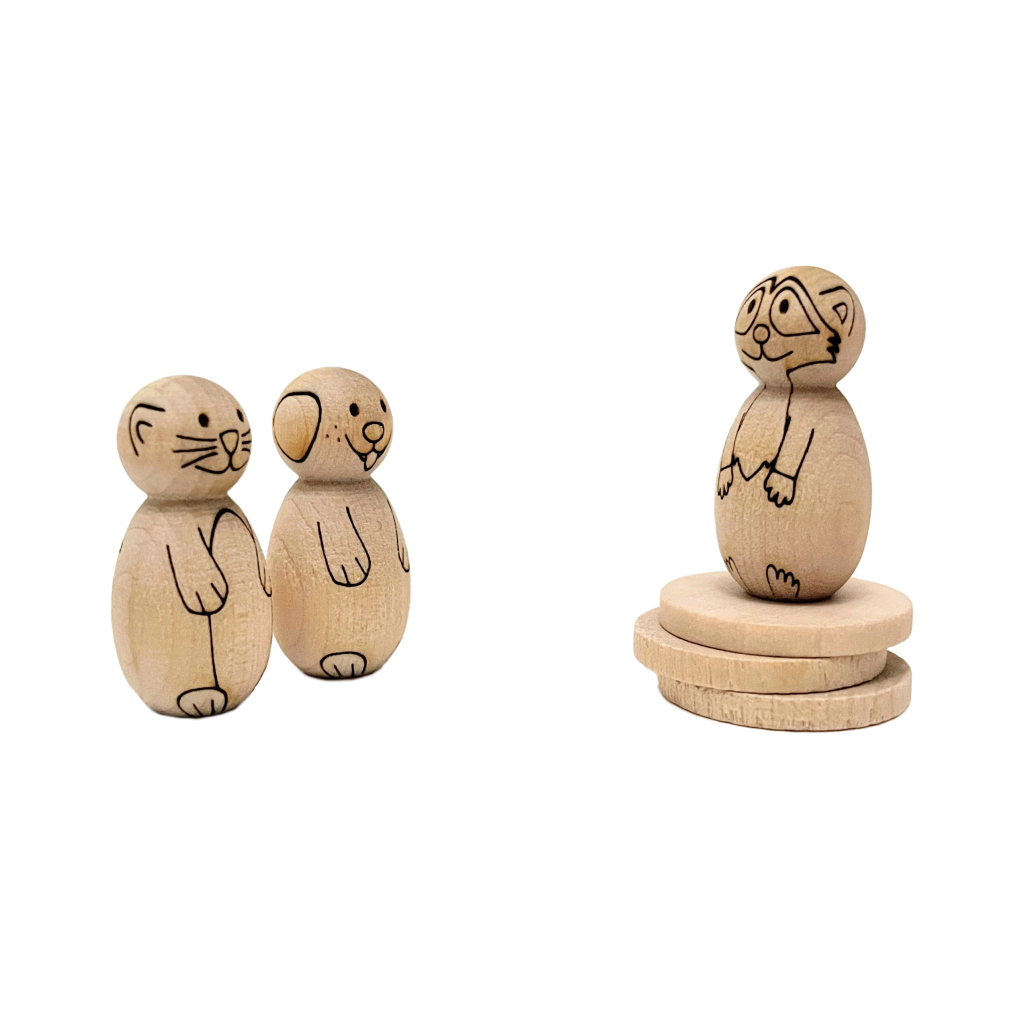 Miniature wooden peg dolls laser engraved to look like a penguin, dog, and cat, looking at each other.