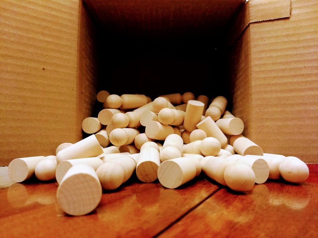 box of blank wooden peg dolls being emptied onto a table